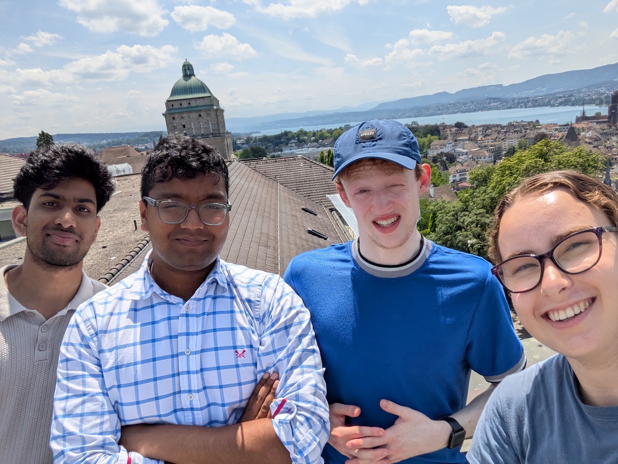 Three men and one woman with the landscape of Zurich in the background